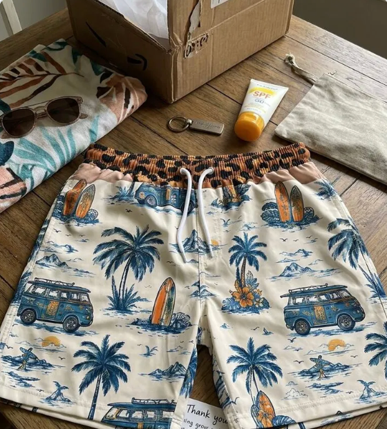 Palm print swim trunks laid out on a wooden deck