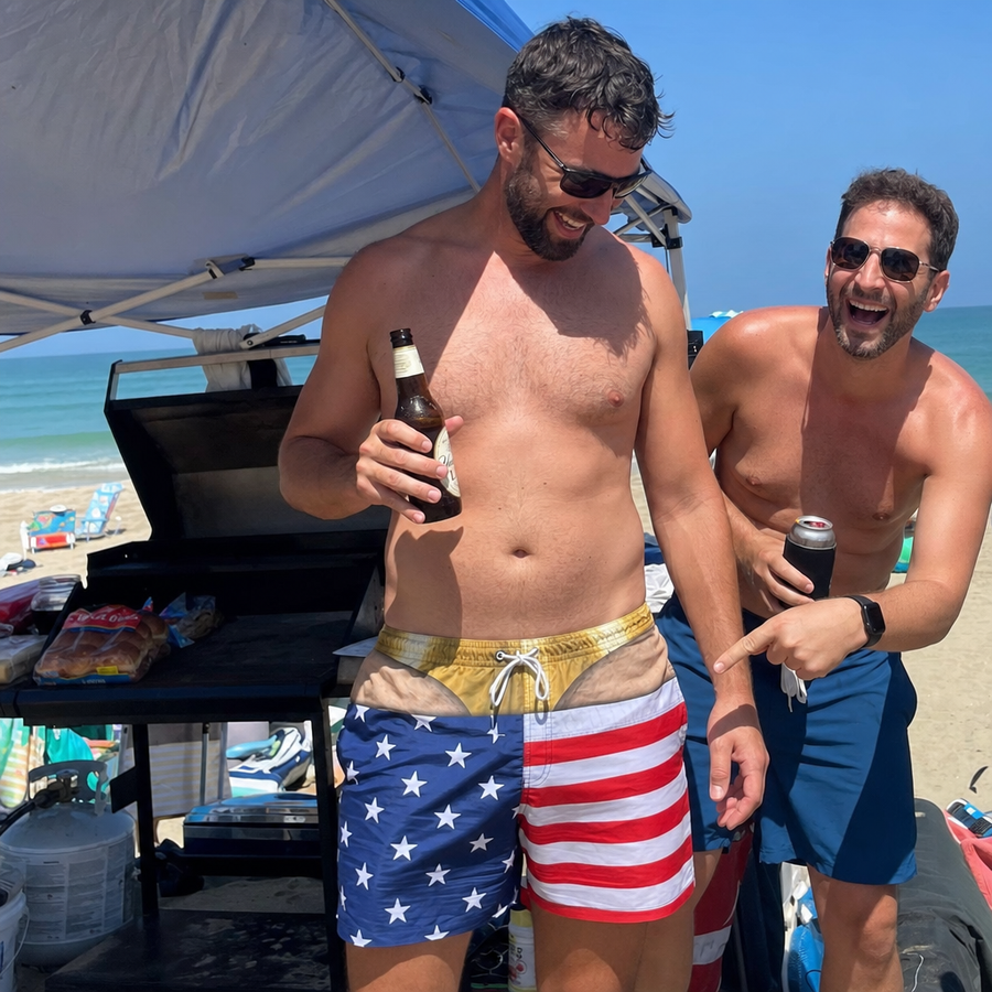 Two friends laughing on the beach in printed swim trunks